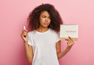 displeased-stressful-dark-skinned-woman-looks-periods-calendar-with-marked-red-crosses (1)