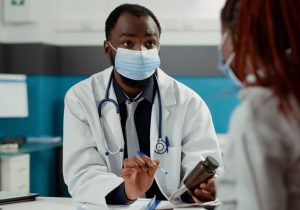 maternity-specialist-pregnant-woman-with-face-mask-checkup-visit-meeting-talk-about-pregnancy-future-mother-with-baby-bump-asking-medical-advice-from-physician-cabinet-desk